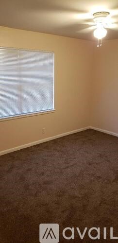 A room with a carpeted floor and a window with blinds.