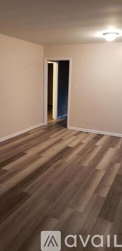 A room with wooden flooring and a doorway leading to another room.