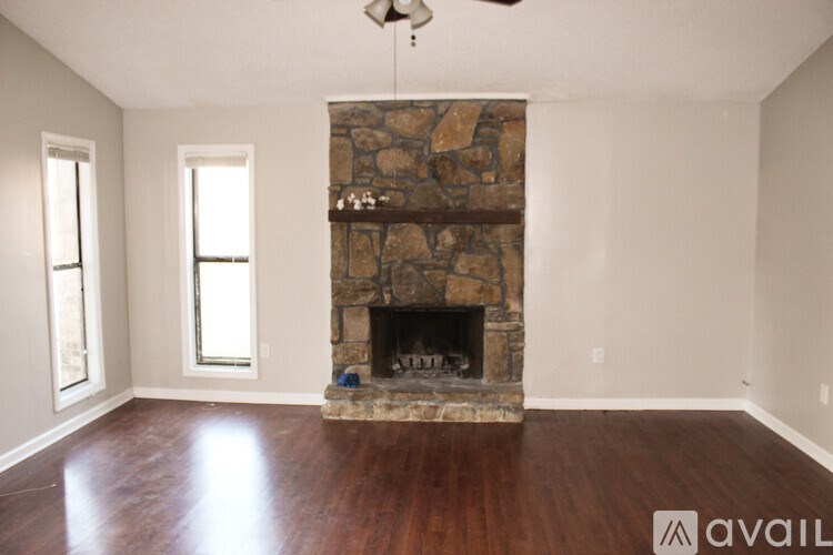 A room with a stone fireplace and wood flooring.