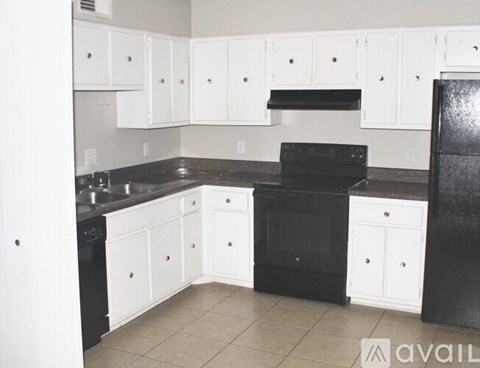 A kitchen with black appliances and white cabinets.