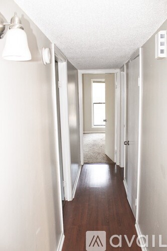 A hallway with white walls and wood flooring.