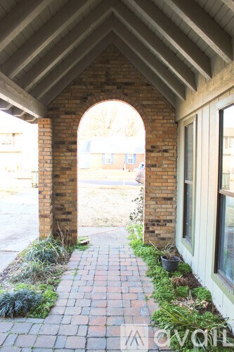 A brick archway leads to a building with a white door.