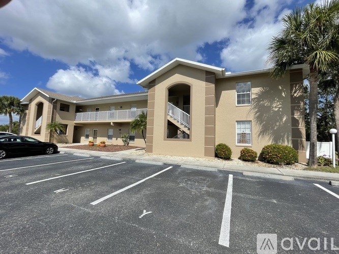 A black car is parked in a parking lot in front of a building.