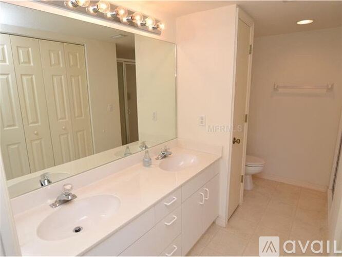 A bathroom with a vanity and a mirror with lights above it.
