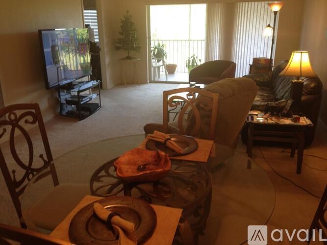 A living room with a television, couch, and chairs.