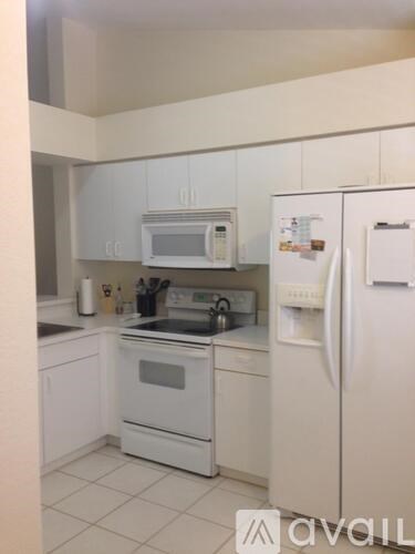 A white kitchen with a fridge and microwave.