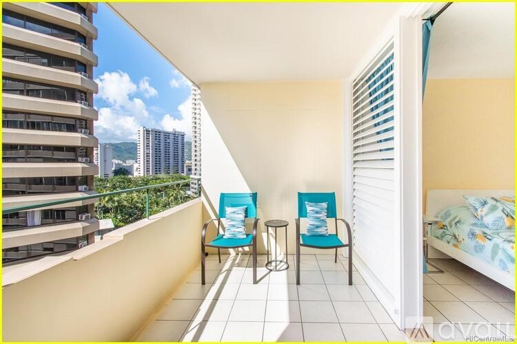 A balcony with two chairs and a table overlooking a cityscape.