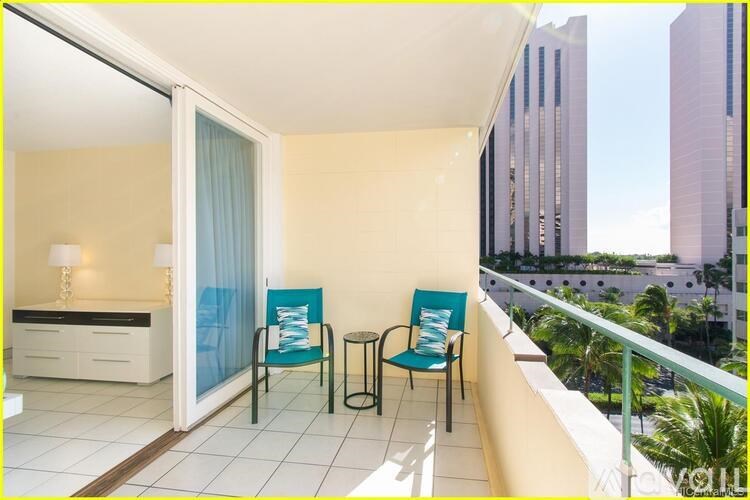 A balcony with two chairs and a table overlooking a cityscape.