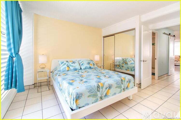 A bedroom with a bed, nightstand, and mirror.