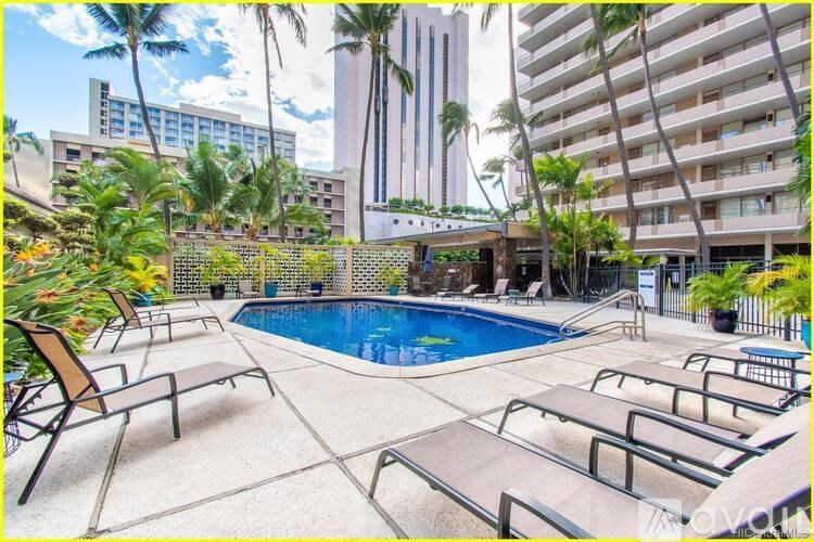A pool surrounded by lounge chairs and palm trees.