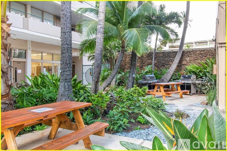 A wooden picnic table is surrounded by green plants and trees.