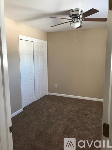 A room with a ceiling fan and carpeted floor.
