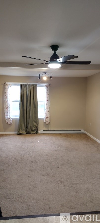 A room with a ceiling fan and carpeted floor.