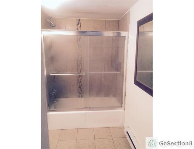 A shower with a glass door and a tiled floor.