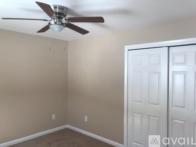 A room with a ceiling fan and a white door.