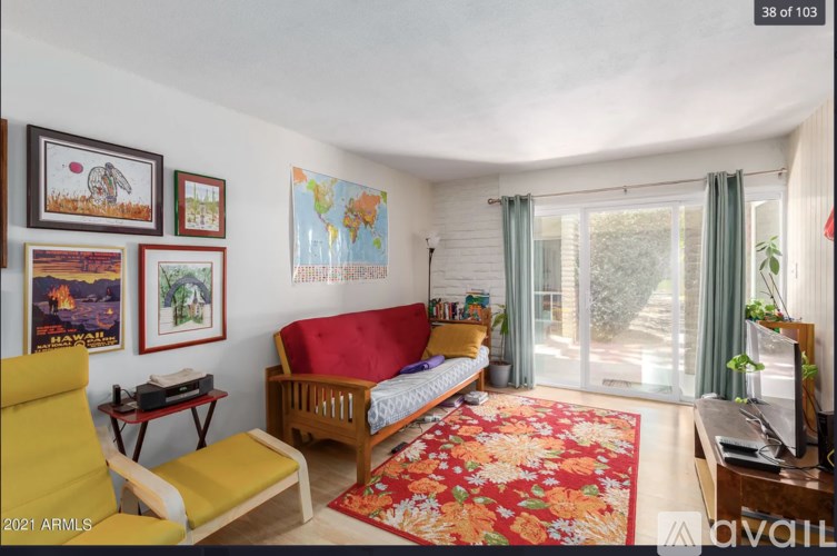 A living room with a red sofa, a yellow chair, and a world map on the wall.