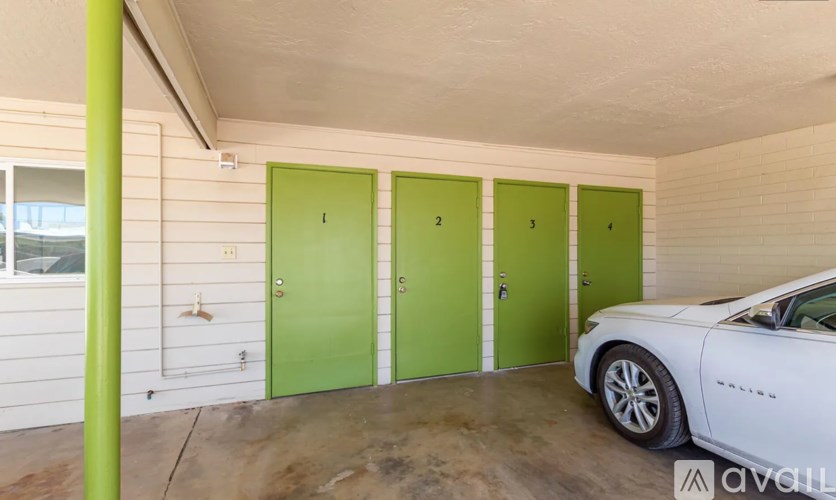 A white car is parked in front of green numbered doors.