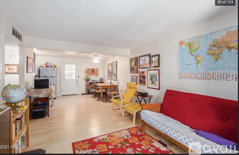 A living room with a red couch and a world map on the wall.