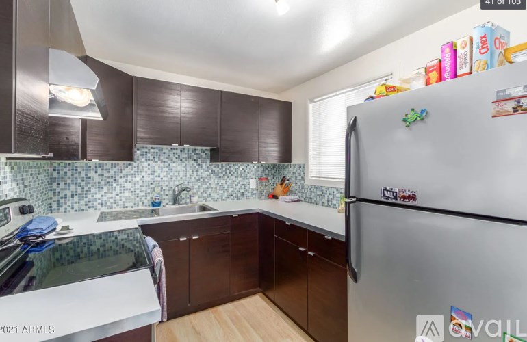 A kitchen with a refrigerator, sink, and cabinets.