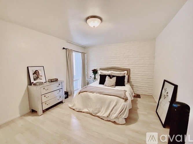 A bedroom with a bed, nightstand, and a picture frame on the wall.