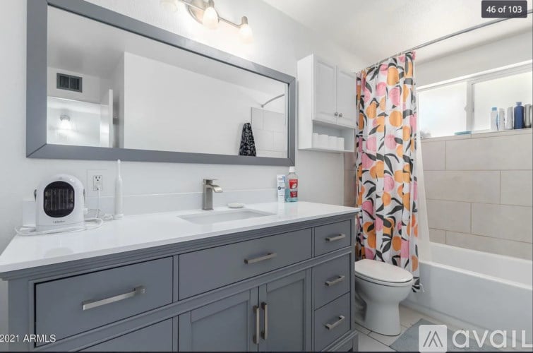 A bathroom with a grey cabinet and a white countertop.