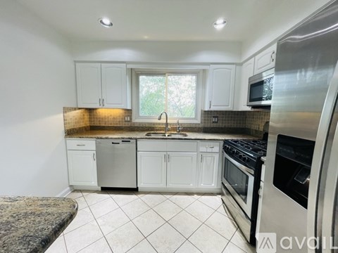 A kitchen with white cabinets and a granite countertop.