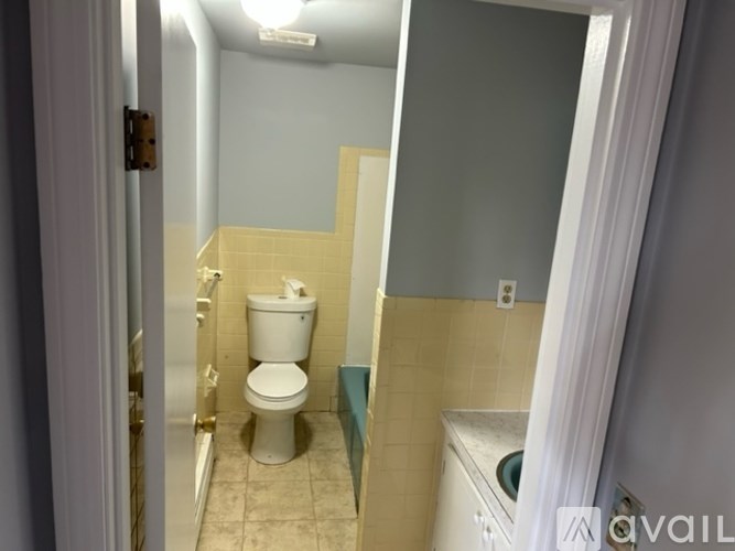 A bathroom with a toilet, sink, and mirror.