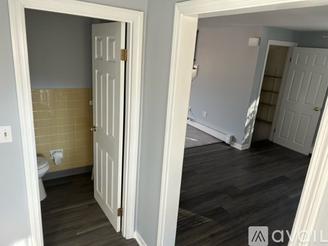 A white door is open to a room with a wooden floor.