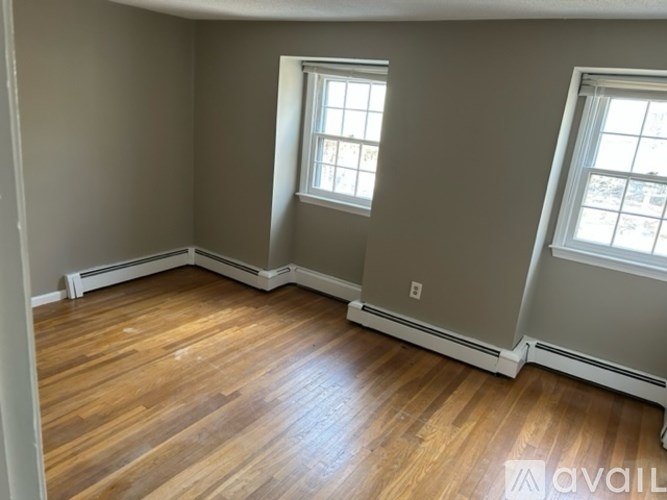 A room with wooden floors and two windows.