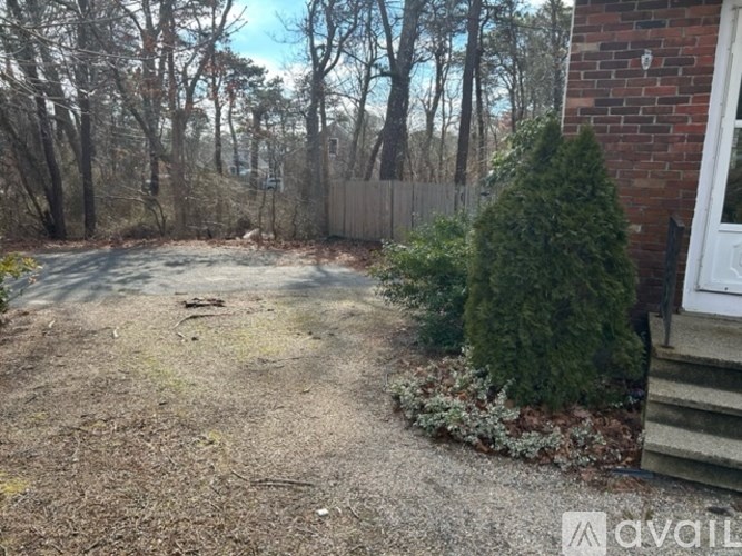 A backyard with a gravel area, a small garden, and a fence.