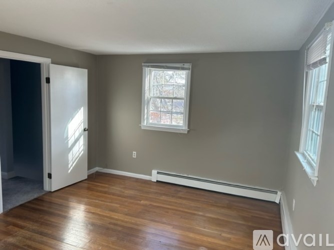 A room with wooden floors and a window with blinds.