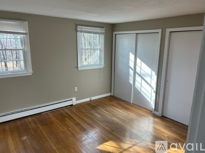 A room with wooden floors and two windows.