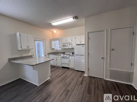 A kitchen with white appliances and cabinets, and a countertop with a granite island.
