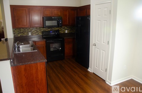 A kitchen with a black refrigerator and wooden cabinets.