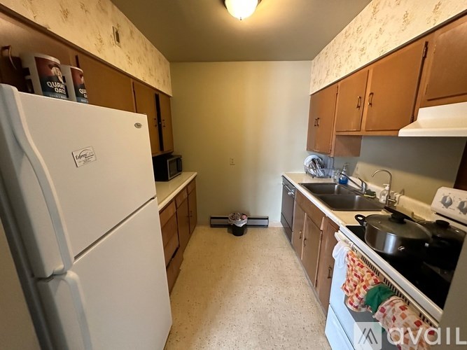 A kitchen with a white fridge and wooden cabinets.