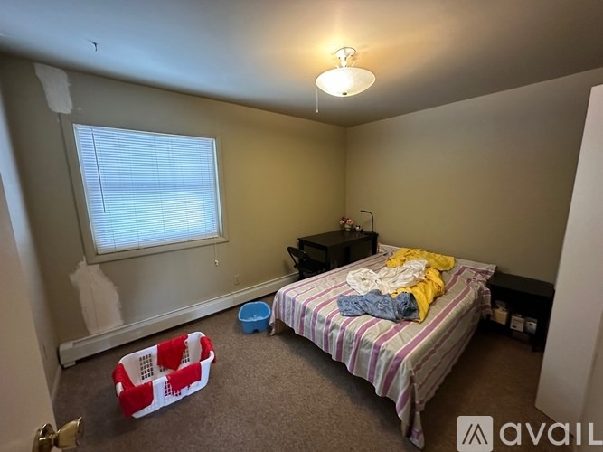 A bedroom with a bed, a small table, and a window with blinds.