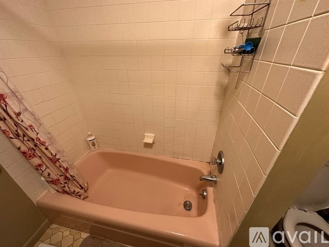 A bathroom with a pink bathtub and white tiled walls.