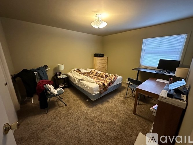 A small bedroom with a bed, desk, and chair.