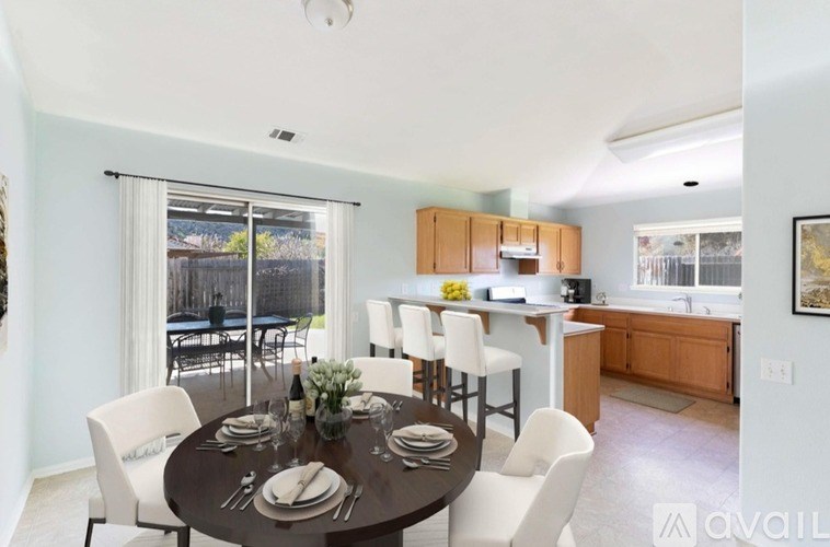 A dining room with a table set for six with a view of a backyard.