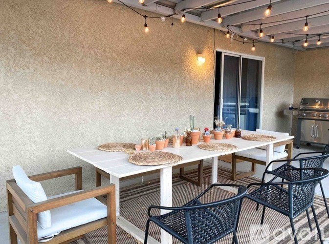 A patio with a table, chairs, and string lights.
