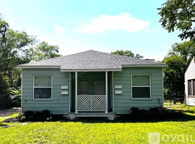A small house with a porch and a white picket fence.