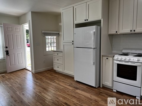 A kitchen with white appliances and wooden floors.