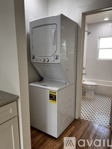 A small white washing machine is in a bathroom.