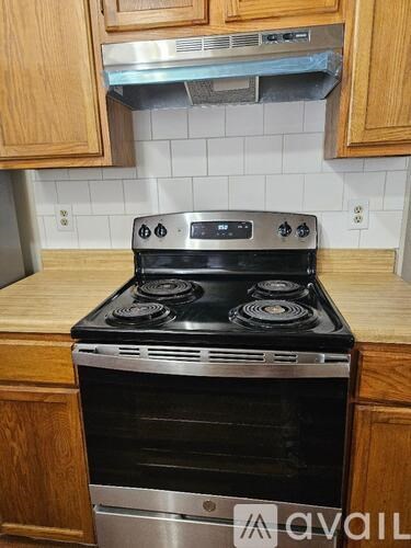 A stainless steel oven with four burners is built into a kitchen counter.
