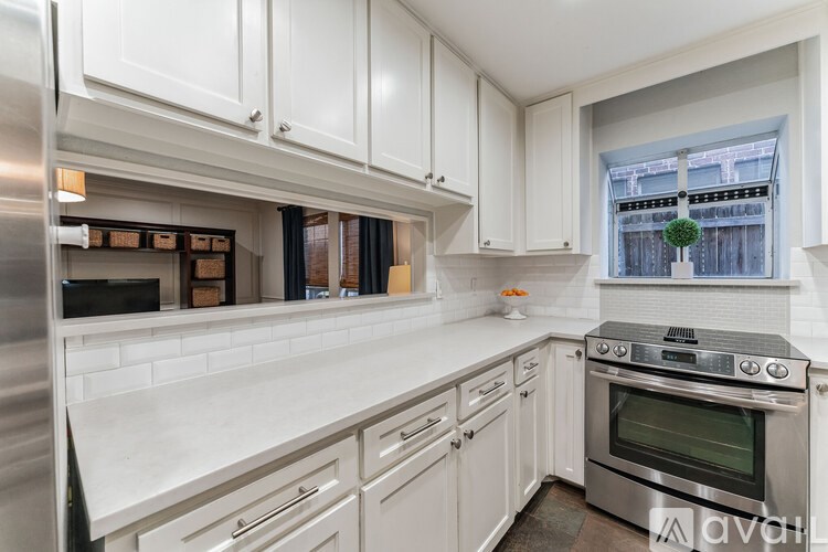 A kitchen with white cabinets and a stainless steel refrigerator.