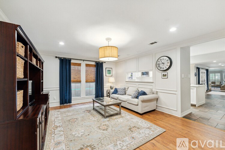 A living room with a white couch and a large rug.