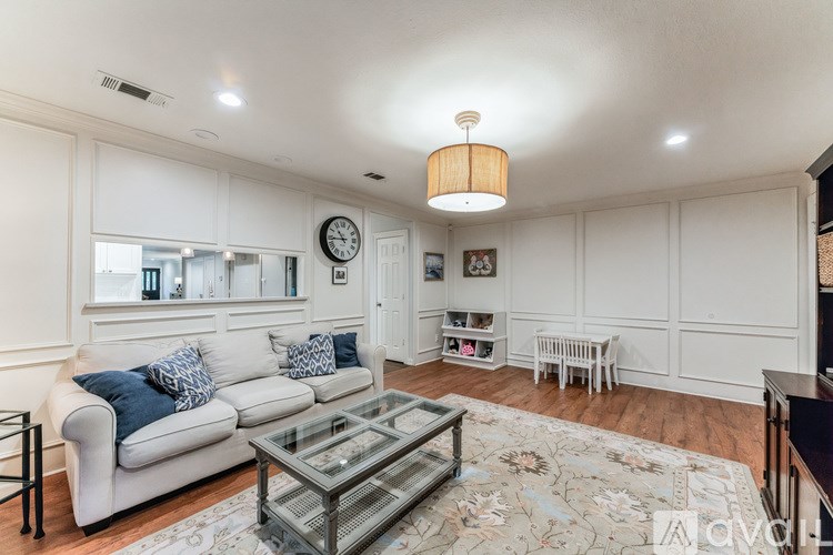 A living room with a white couch and a glass coffee table.