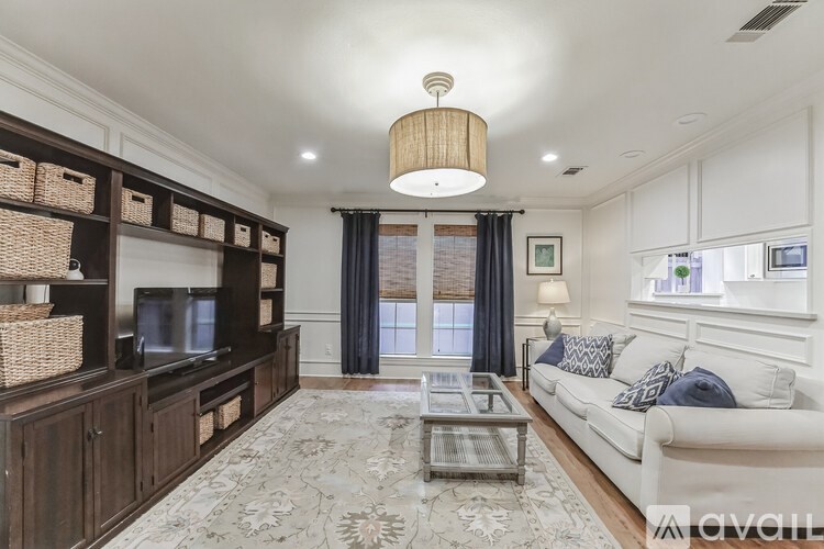 A living room with a white couch, a coffee table, and a television.