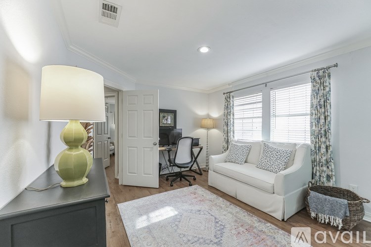 A well-lit living room with a white couch and a green lamp.
