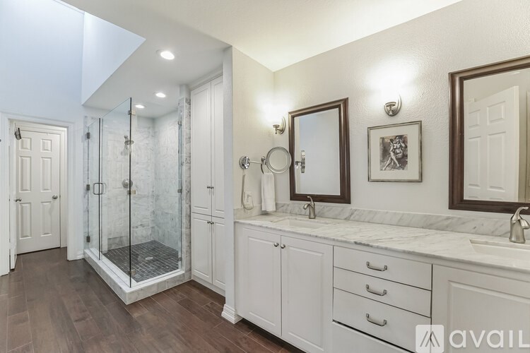 A bathroom with a walk-in shower and double sinks.